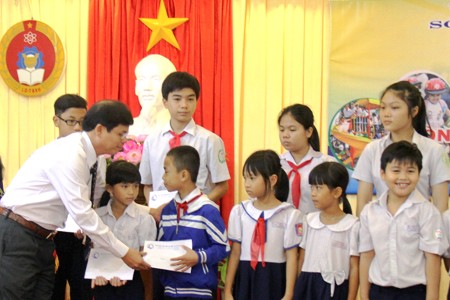 Ông Nguyễn Tấn Tuân trao học bổng cho học sinh vượt khó vươn lên trong học tập.