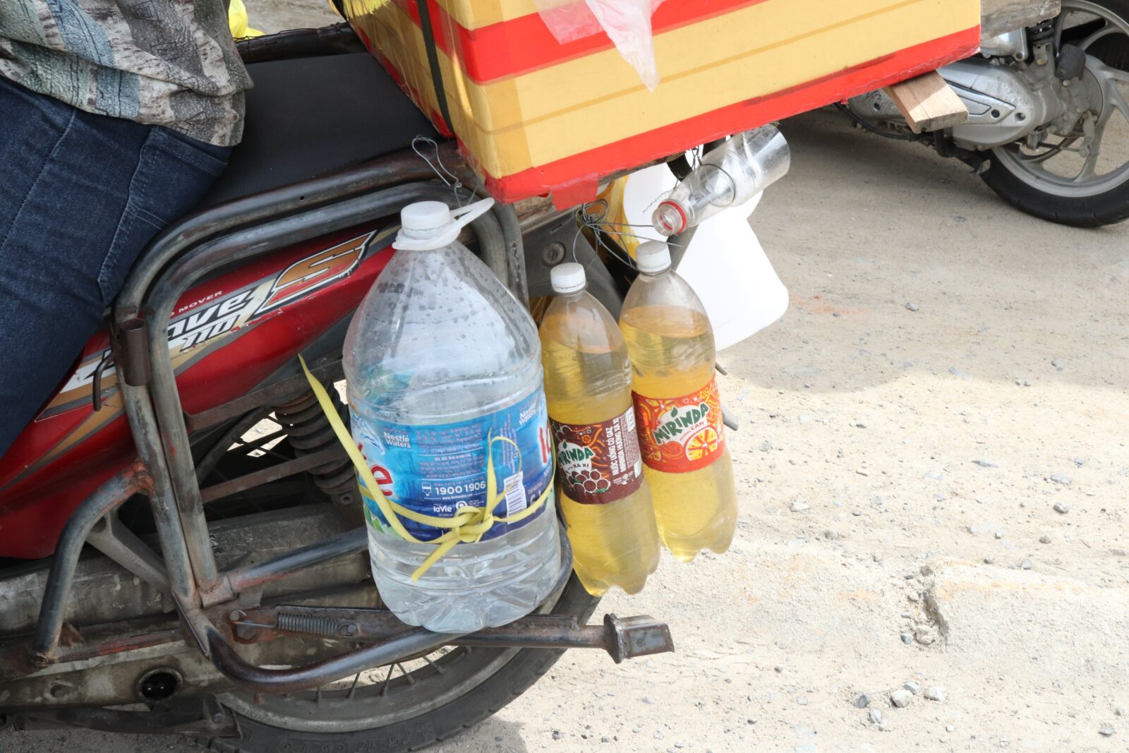 Xăng và nước uống được người lao động buộc ở sau xe máy trên chặng đường về quê.